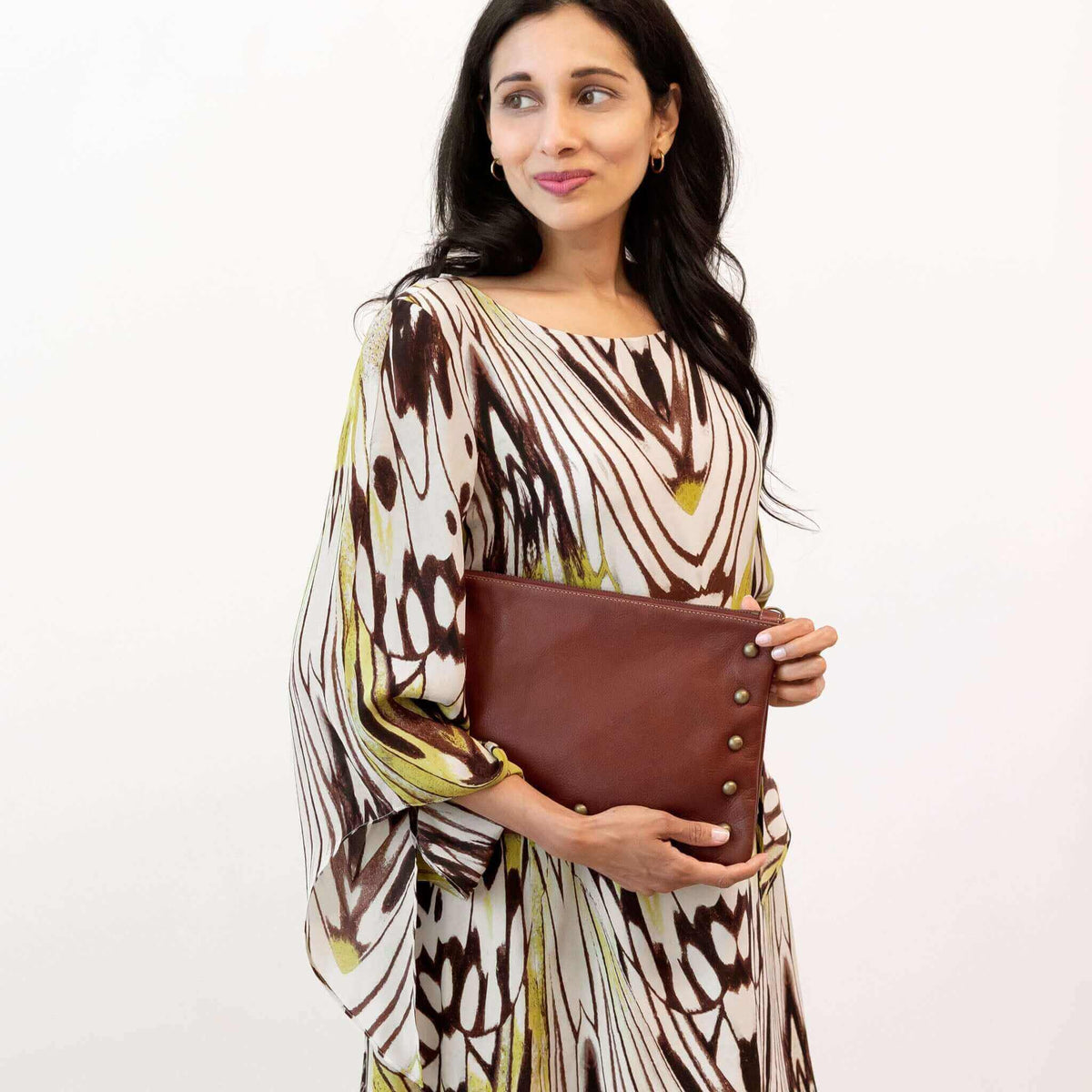 Woman wearing wine studded crossbody bag as a clutch bag in studio