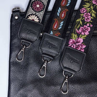 Three stylish guitar bag straps featuring floral and paisley prints on a black leather background.