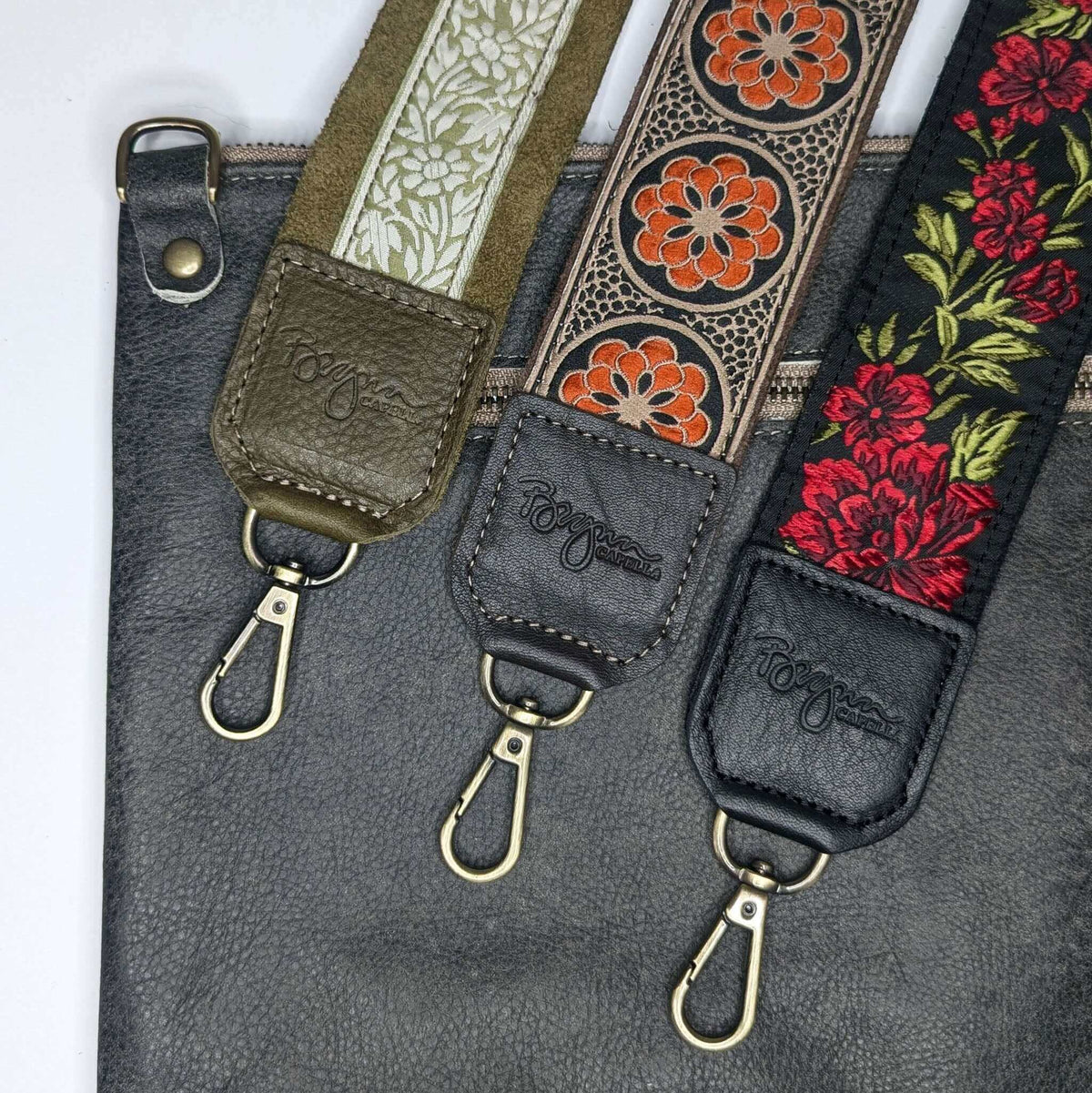 Back view of light charcoal full-grain leather bag paired with three matching guitar purse straps in woven jacquard prints