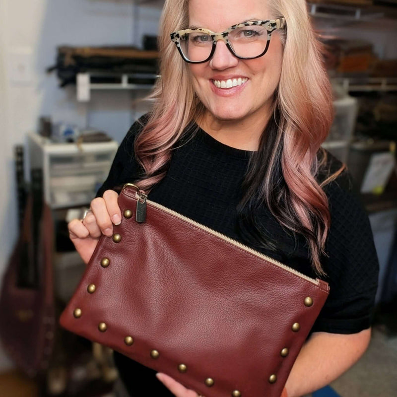 Woman smiling and holding a Nikki Studded Crossbody Bag with gold studs.