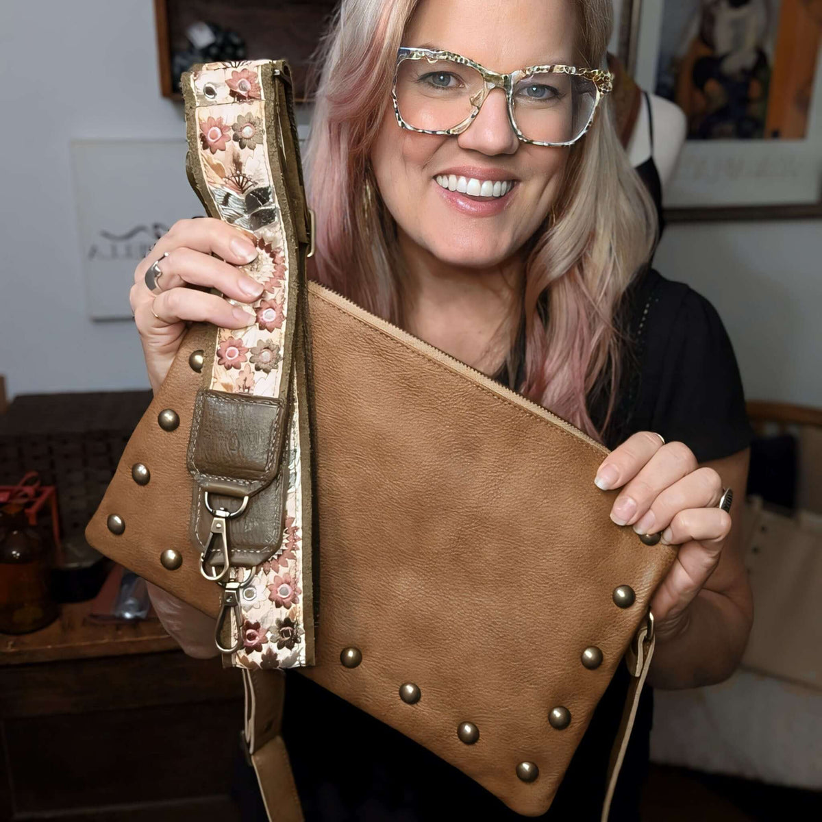 Designer Brynn Capella holding a golden brown studded crossbody bag with our Chocolate Sunflower Lizzy bag strap