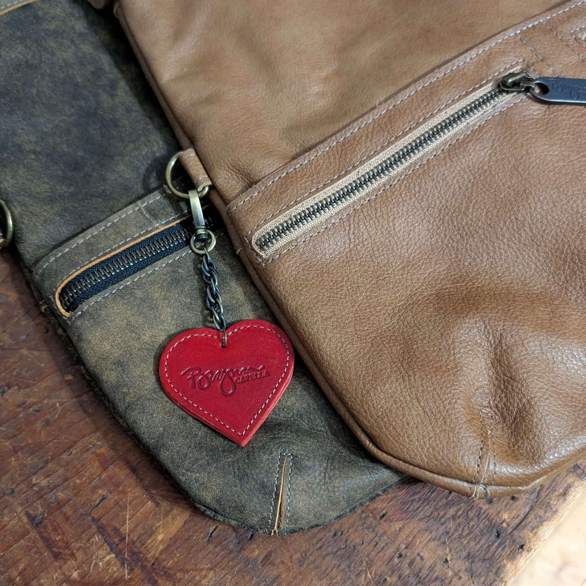 Red heart bag charm attached to a leather bag, showcasing the design and style of bag charms.