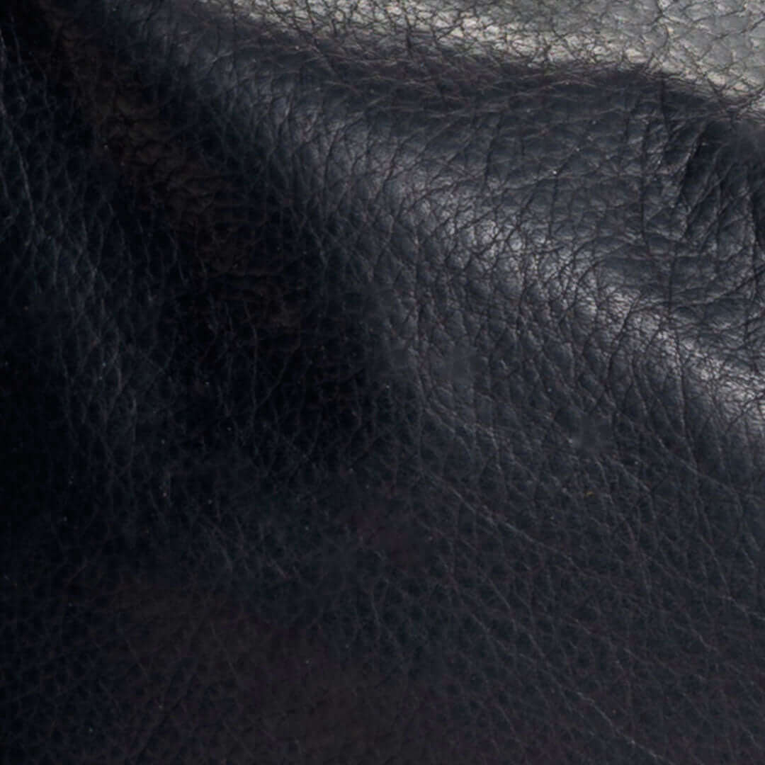 Close-up of the soft texture of original black leather crossbody bag material.