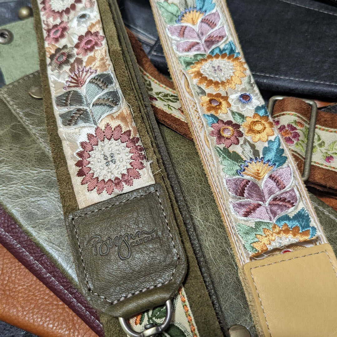 Close-up of Lizzy Guitar Bag Strap - Golden Sunflower with intricate floral embroidery on a leather background.