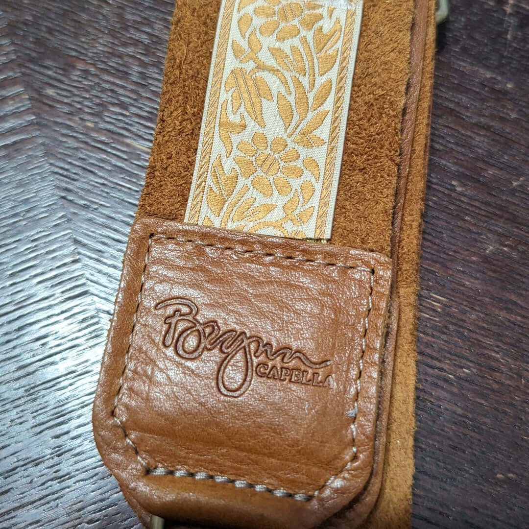 Close-up of Brynn Capella leather guitar bag strap with floral print and embossed logo, ideal as a stylish guitar bag strap.