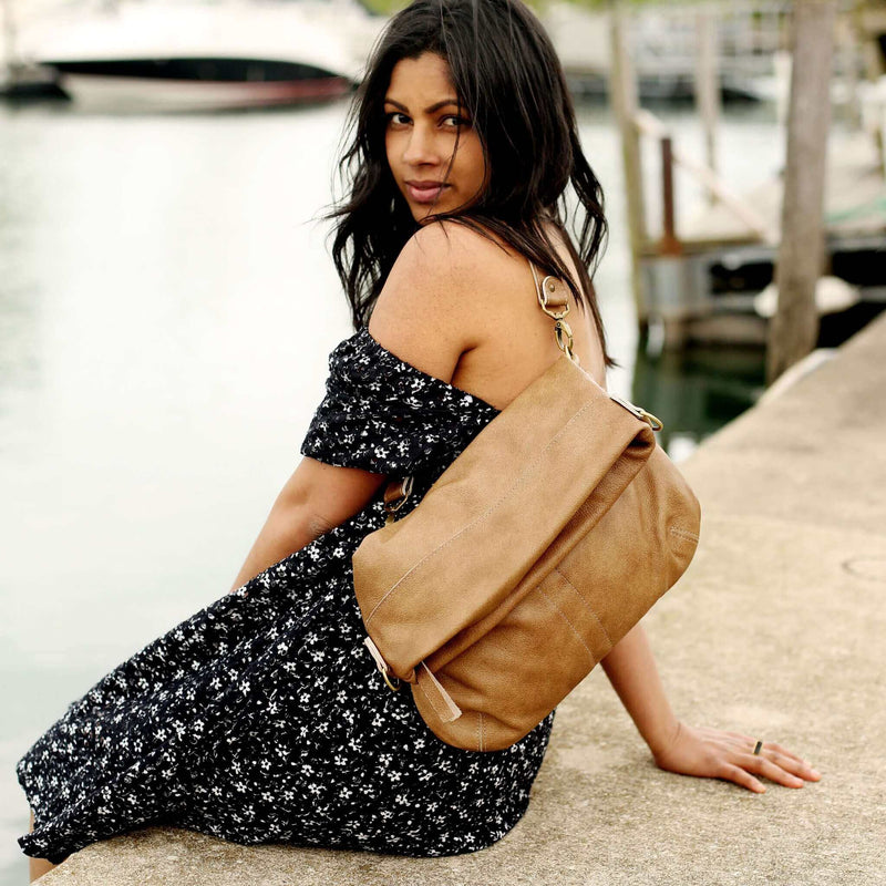 Woman wearing an Original Lauren leather crossbody bag on the shore by water, showcasing its stylish design.