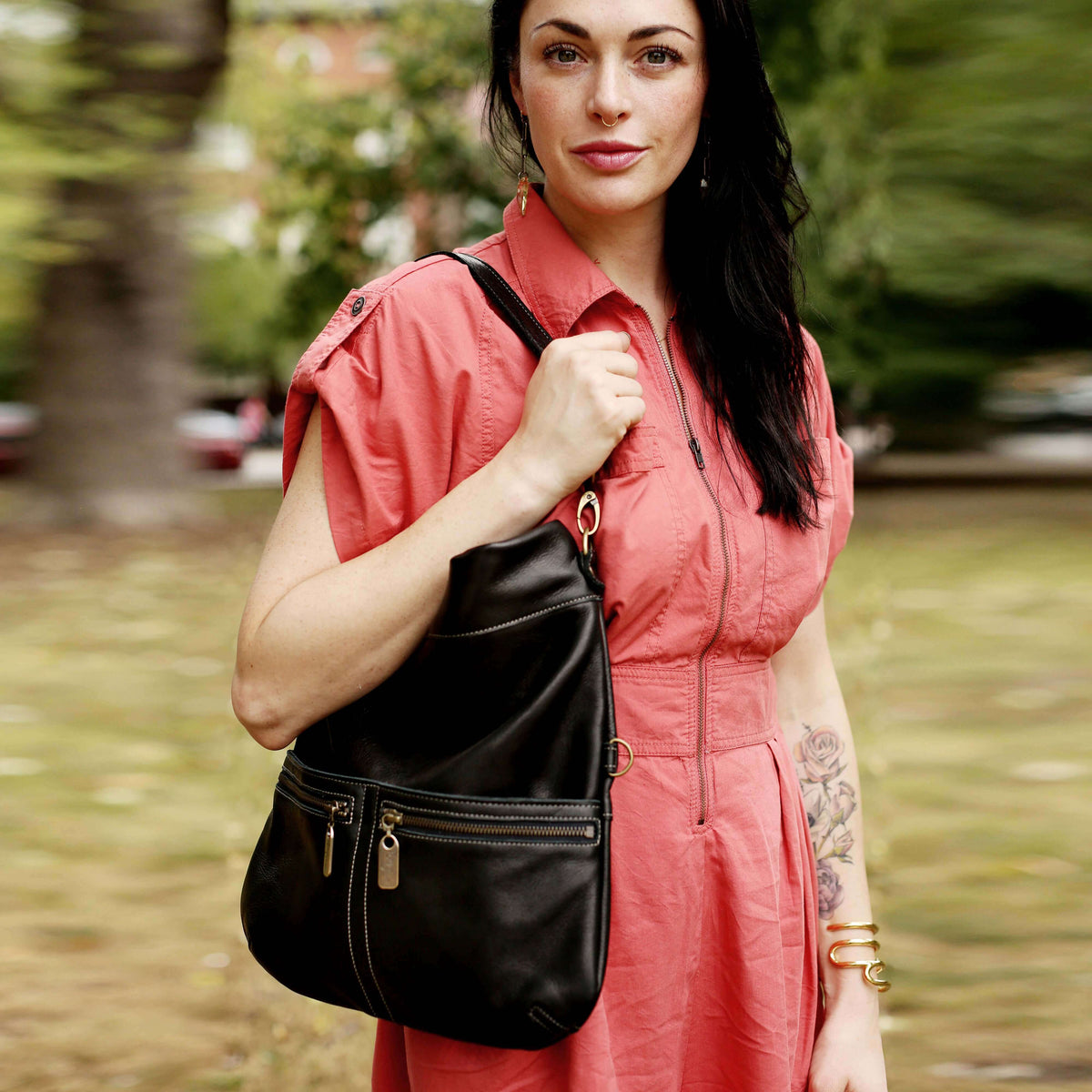 Woman holding a Mini Lauren leather crossbody bag in black sand while wearing a pink dress.