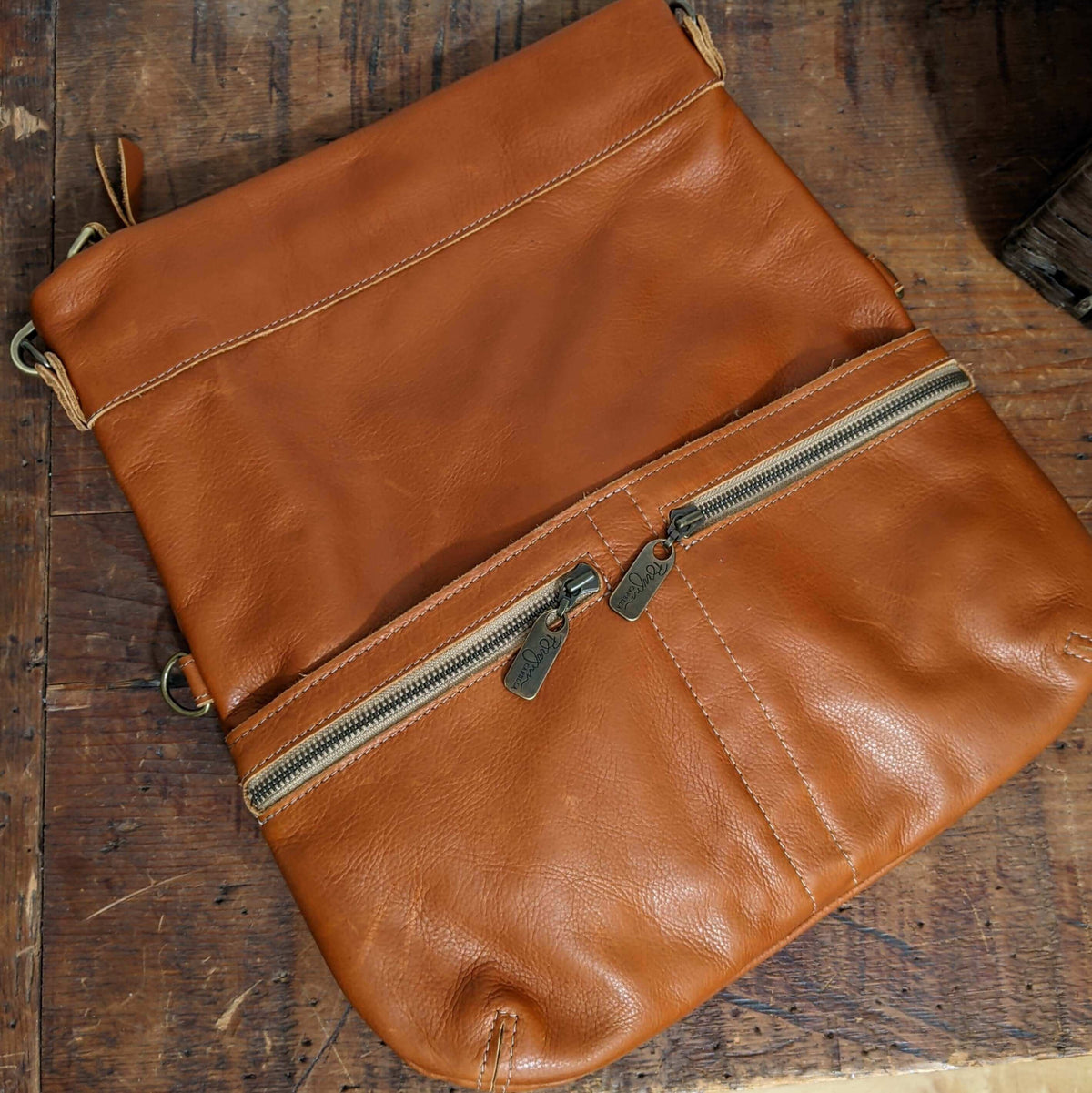 Mini Lauren 6-in-1 Convertible Leather Crossbody Bag in Whiskey with zippers on a wooden surface.