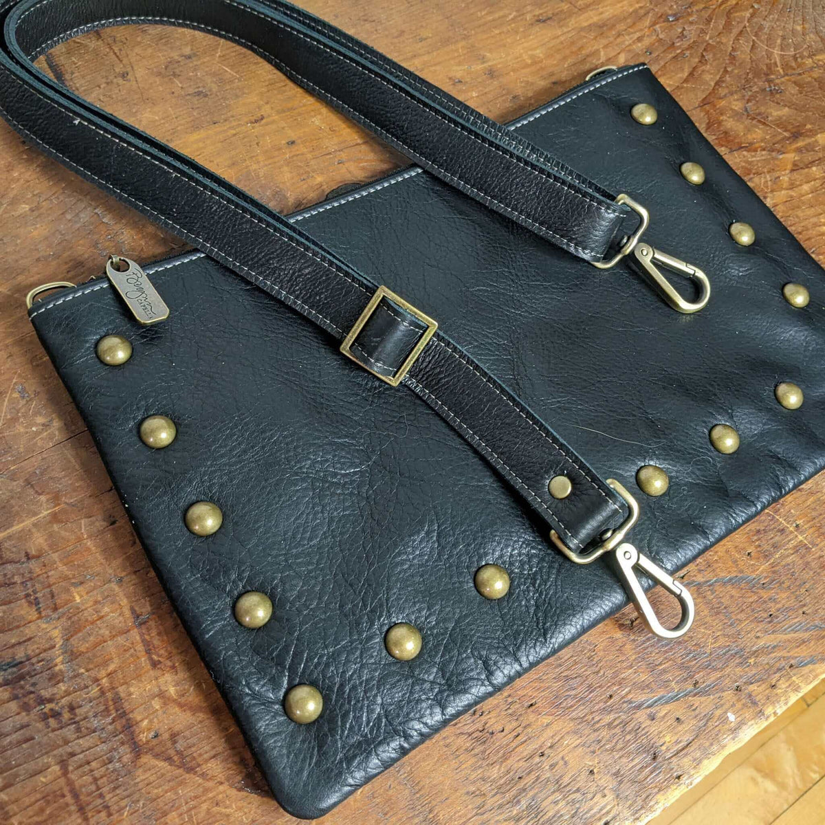 overview of Studded bag in black full-grain leather convertible clutch-to-crossbody with adjustable strap