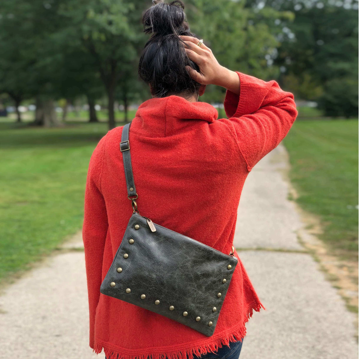 Woman wearing dark charcoal studded crossbody bag in full-grain leather as a small crossbody bag with adjustable strap